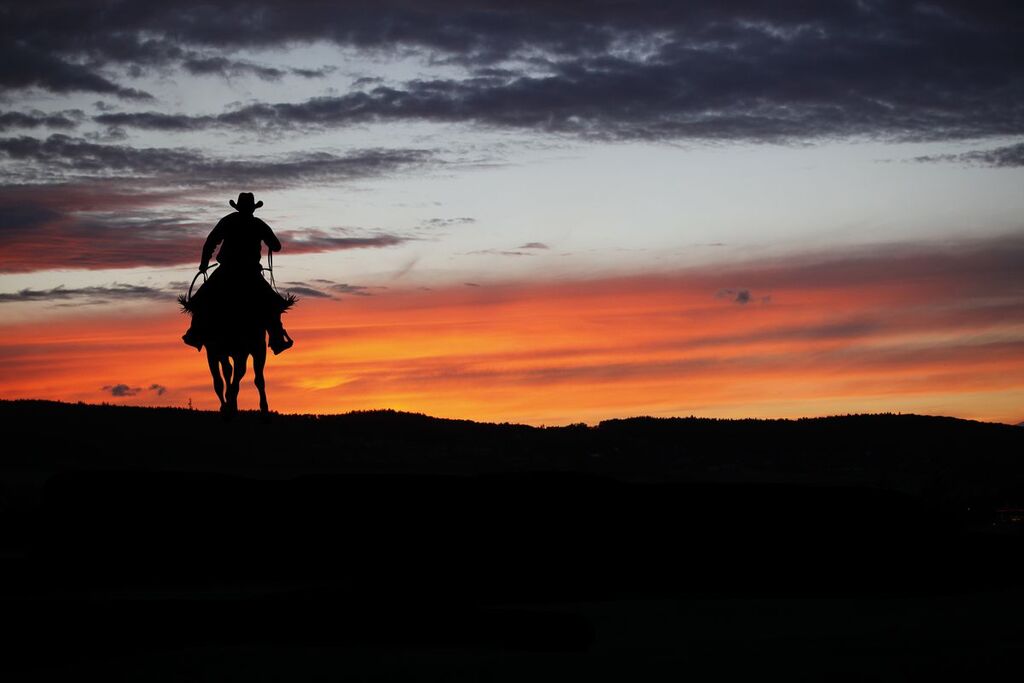 Un cowboy a cavallo al tramonto